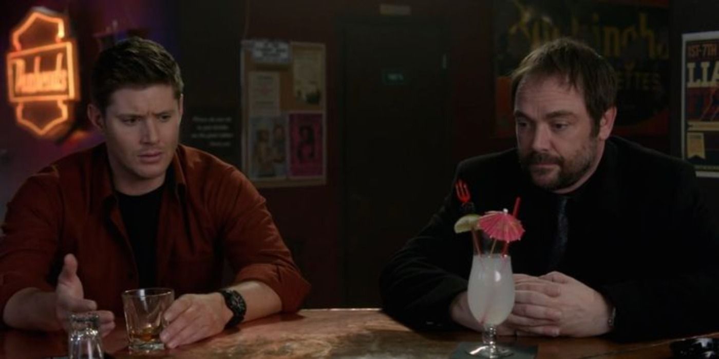 Dean and Crowley share drinks with one another in Supernatural