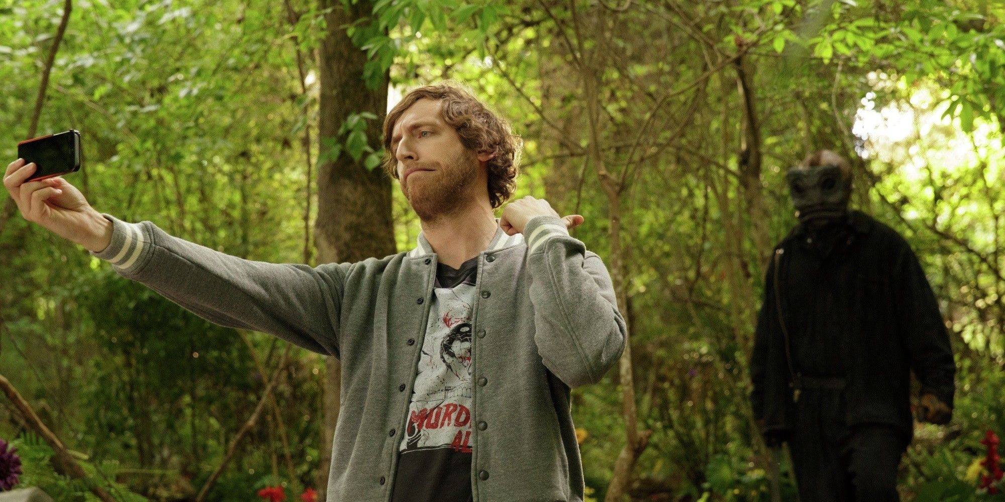 A killer sneaks up on Duncan as he holds up his phone in The Final Girls