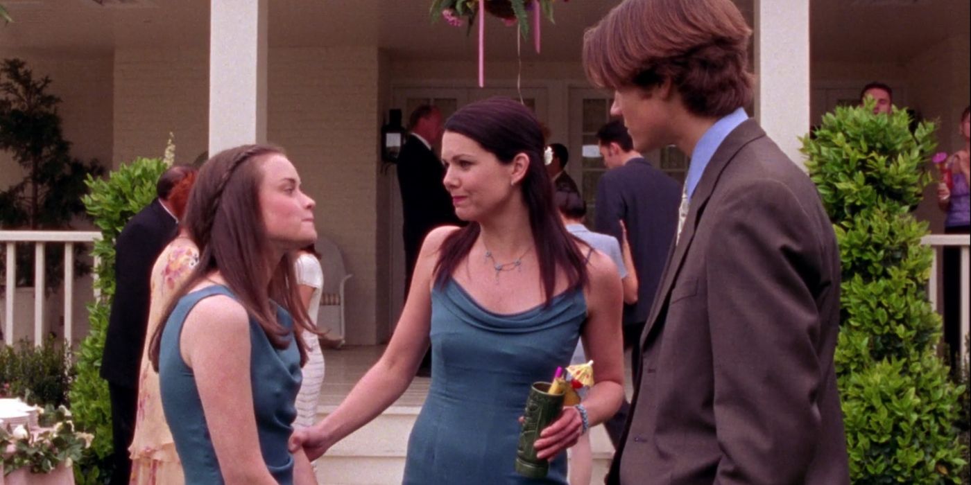 Rory and Lorelai in bridesmaids dresses standing with Dean on Gilmore Girls