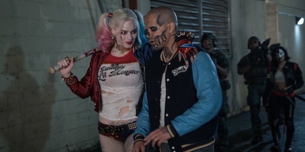 Harley Quinn walks with her arm around El Diablo in Suicide Squad