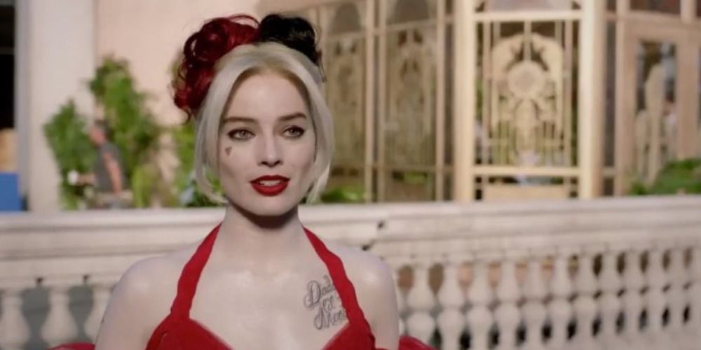 Harley Quinn in The Suicide Squad wearing a red dress, stood on a balcony of a palace in The Suicide Squad