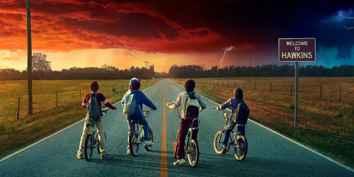 The four kids from Stranger Things on bikes next to the Welcome to Hawkins sign