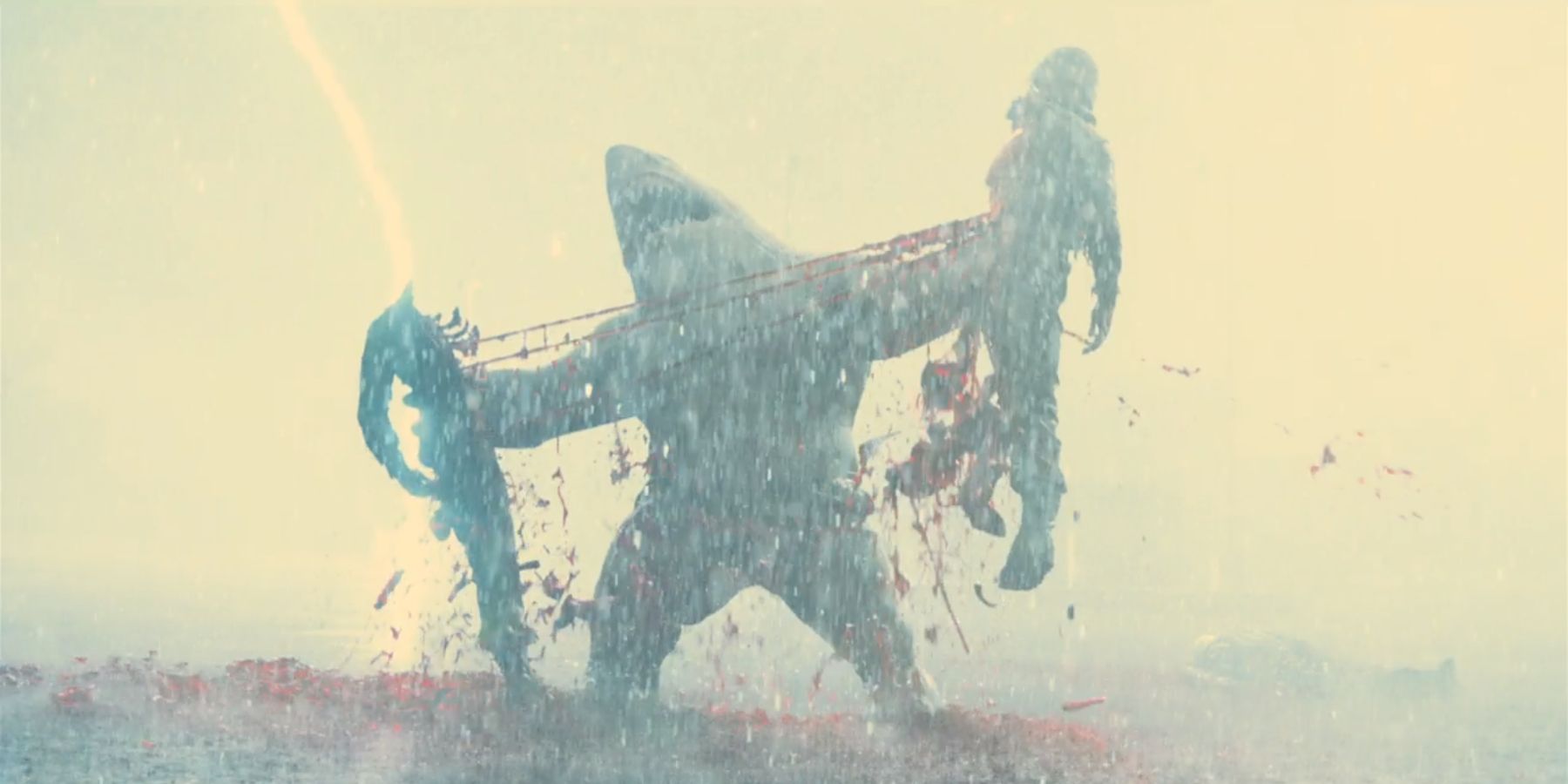 King Shark tearing a man in half while lightning strikes behind him in James Gunn's The Suicide Squad