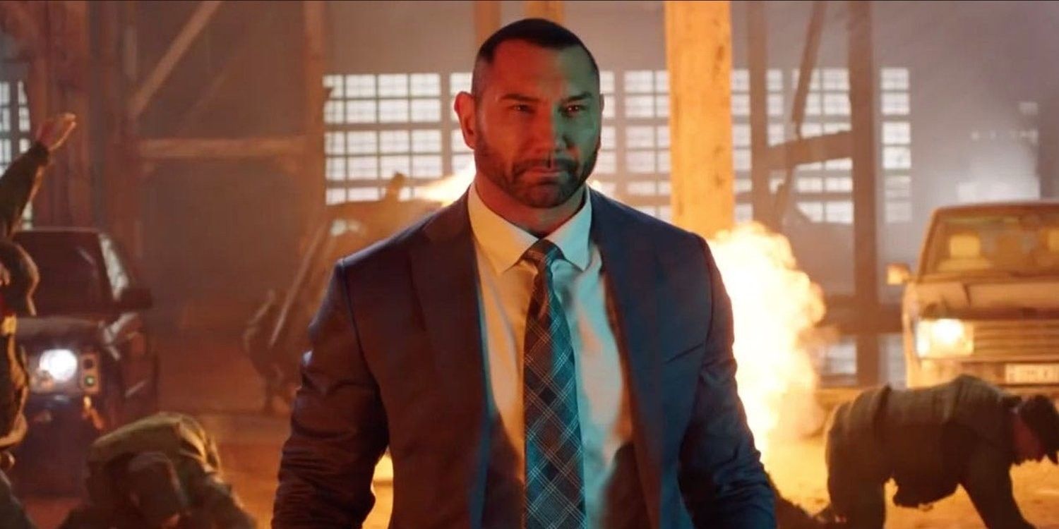 Dave Bautista in a suit walking away from a fire
