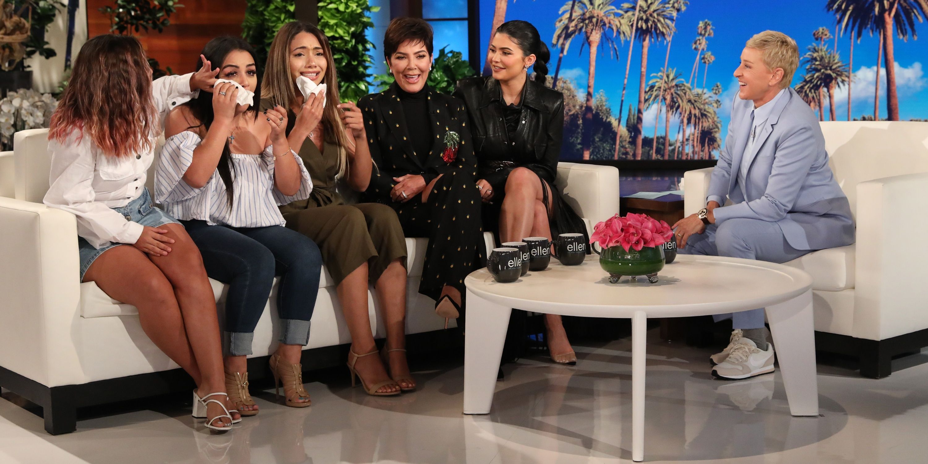 Kris and Kylie Jenner in black sitting at the end of the couch along with members of a charity on Ellen's show