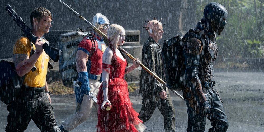 Harley Quinn and her crew storm through the rain with weapons in tow in The Suicide Squad