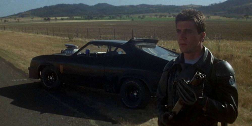 Mel Gibson holding a shotgun at the side of the road in Mad Max