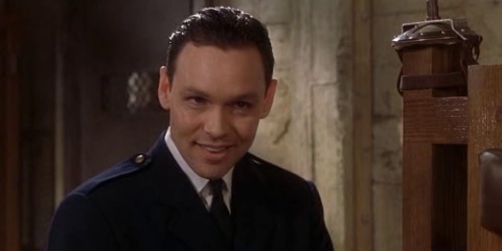 Percy Wetmore from The Green Mile, smirking next to a chair with a chain on it