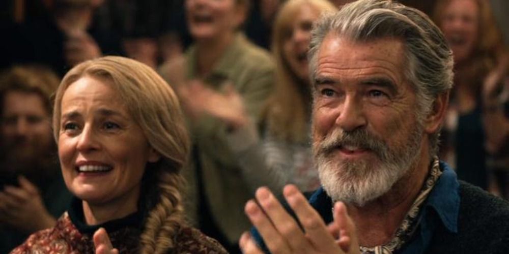 Pierce Brosnan in Eurovision Song Contest The Story of Fire Saga smiling and clapping next to a blonde woman