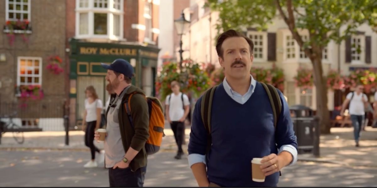 Ted Lasso walking through Richmond with his coffee cup