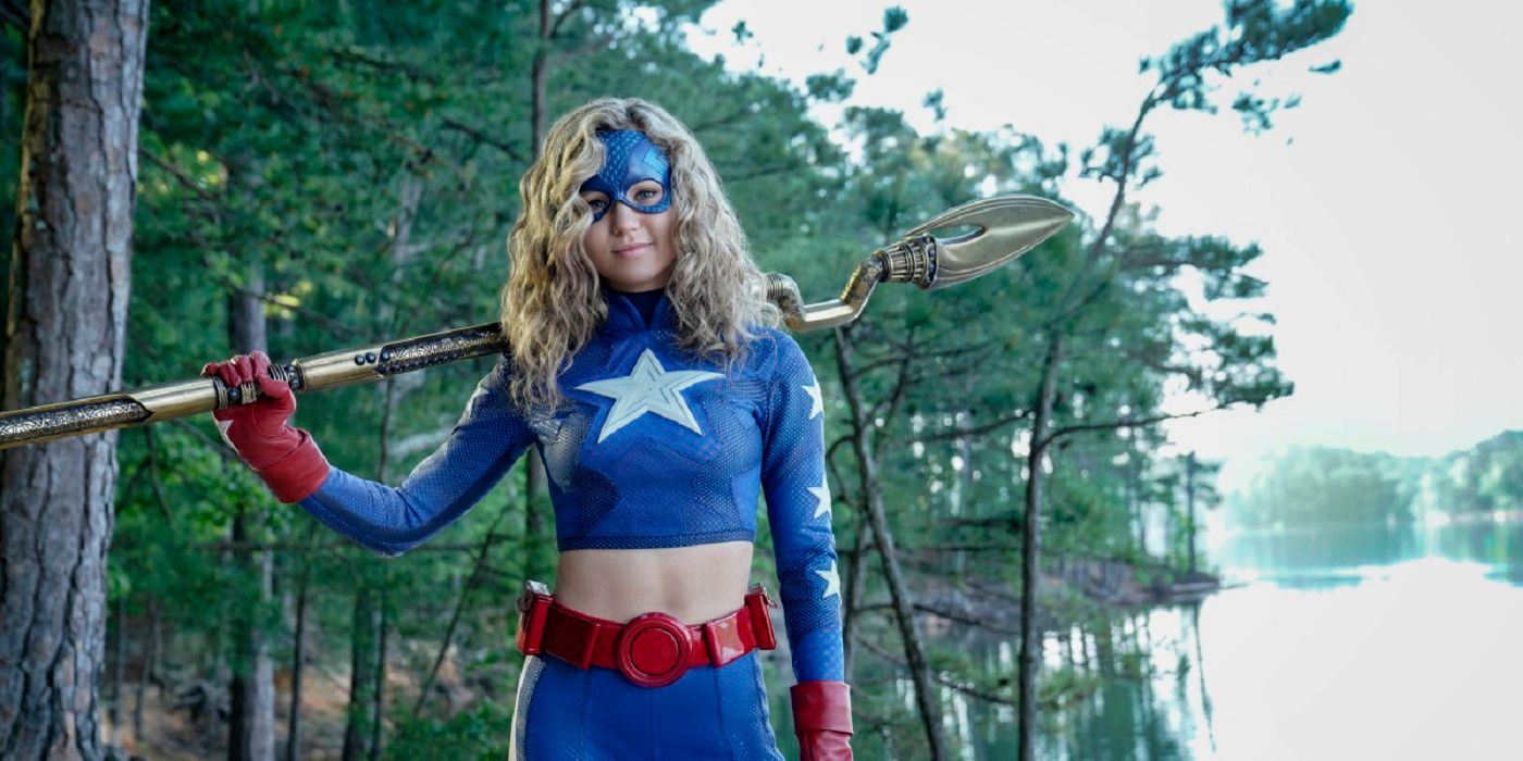 Courtney stands near the trees with her staff and in uniform in Stargirl