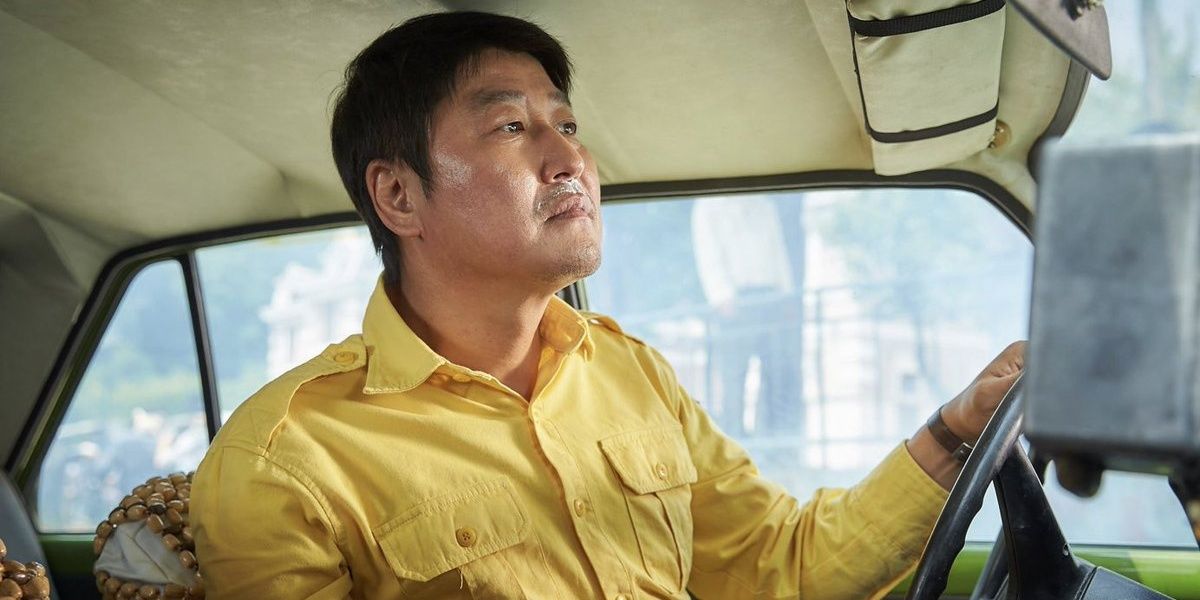 Song Kang-Ho driving a taxi with his hand on the steering wheel in A Taxi Driver