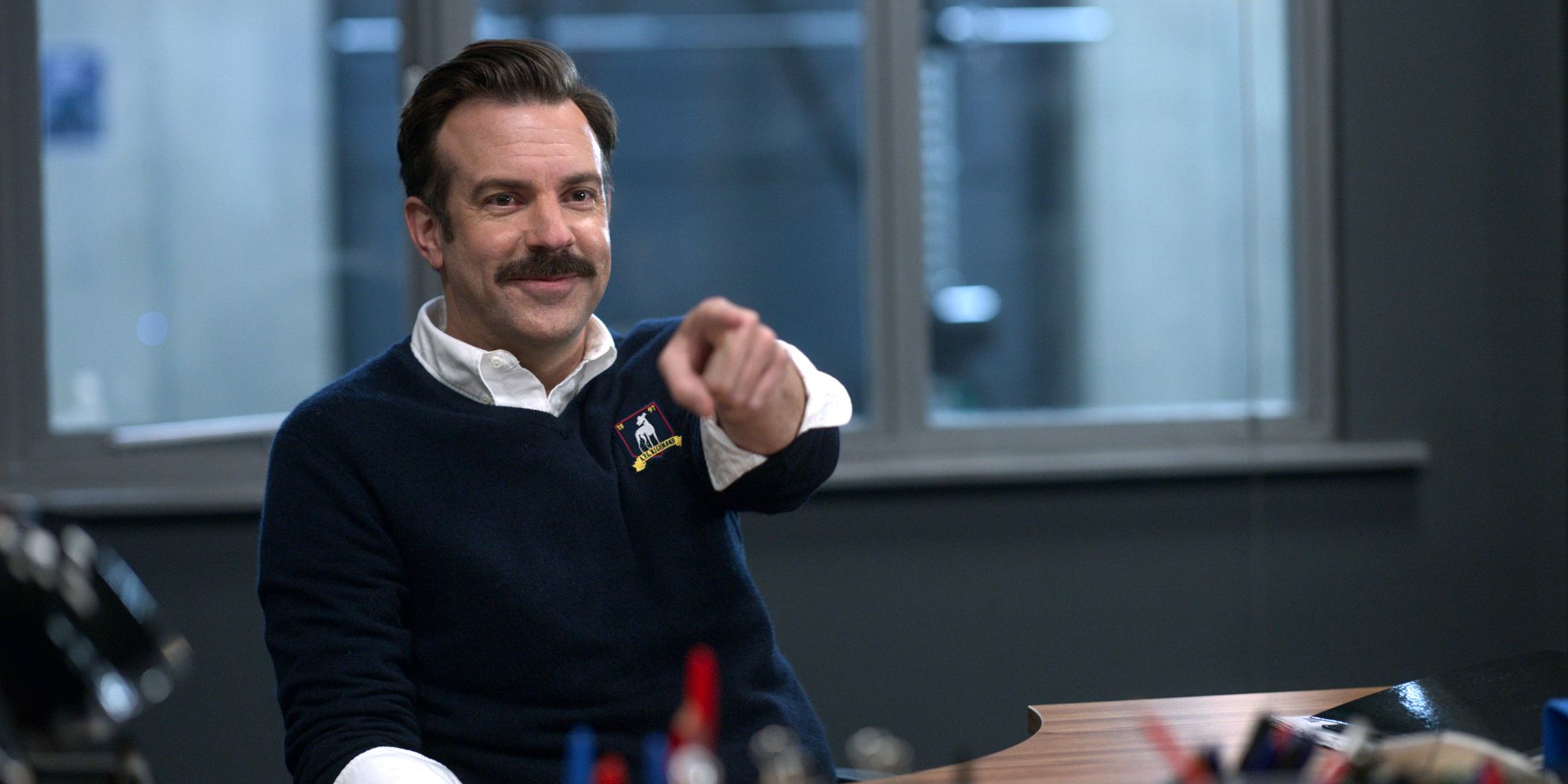 Ted Lasso smiles and points at someone