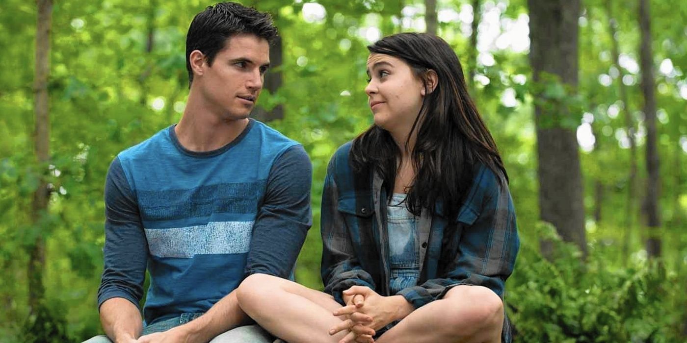 Bianca and Wesley sitting on a log in the woods in The DUFF