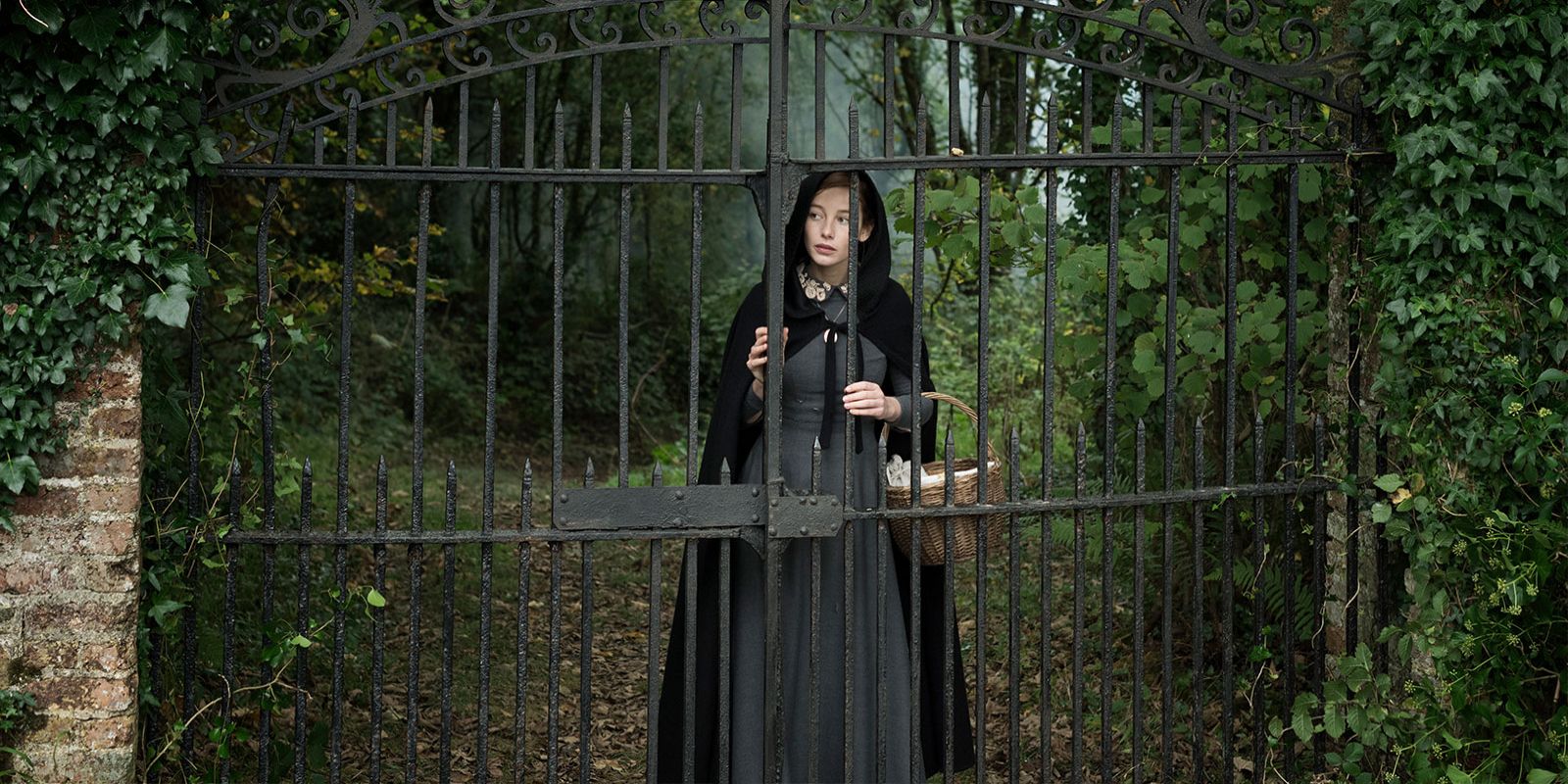 Rachel stands behind the gates of her house in the film The Lodgers.