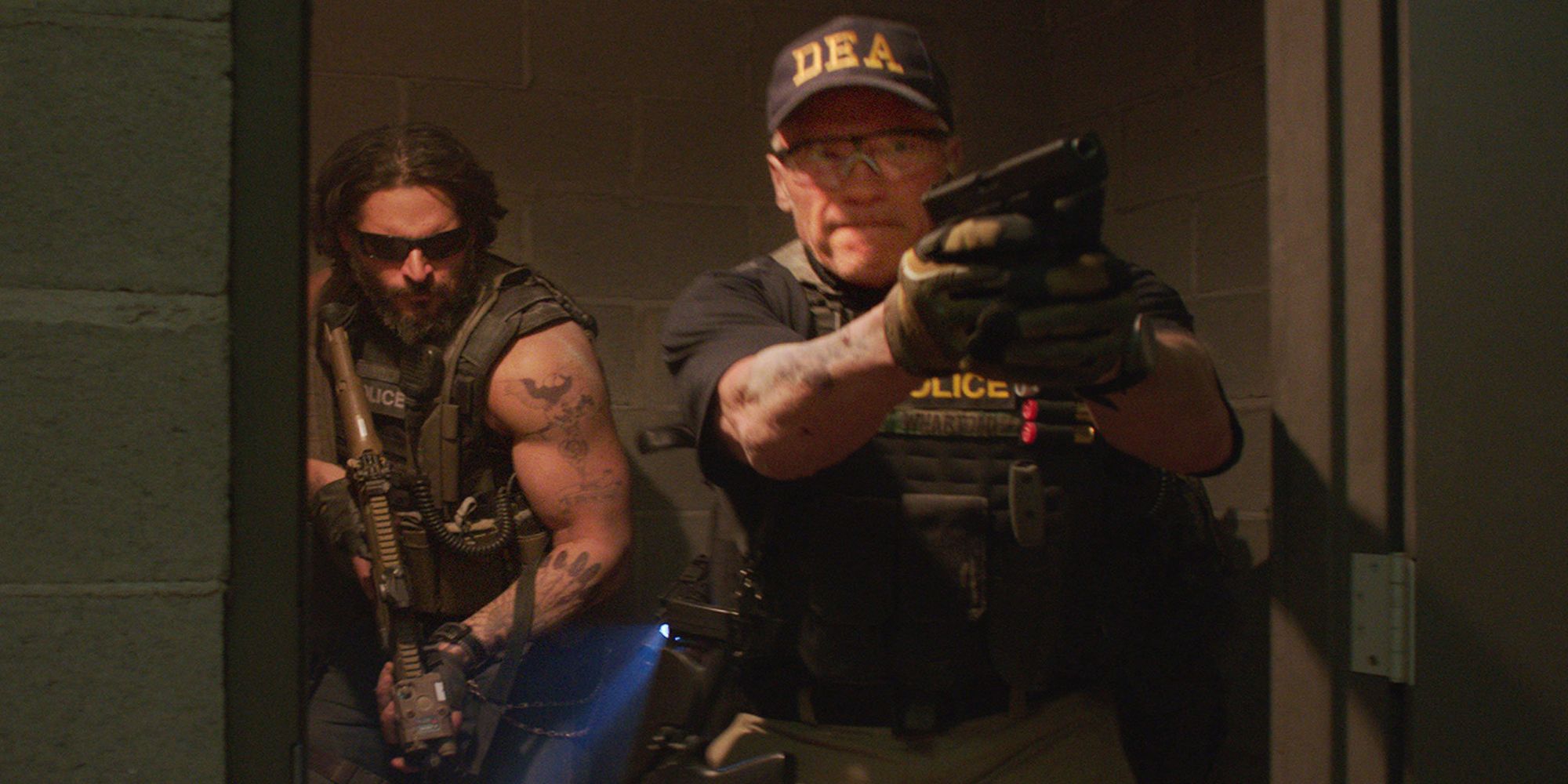 Arnold Schwarzenegger in DEA uniform and firing a gun in Sabotage 
