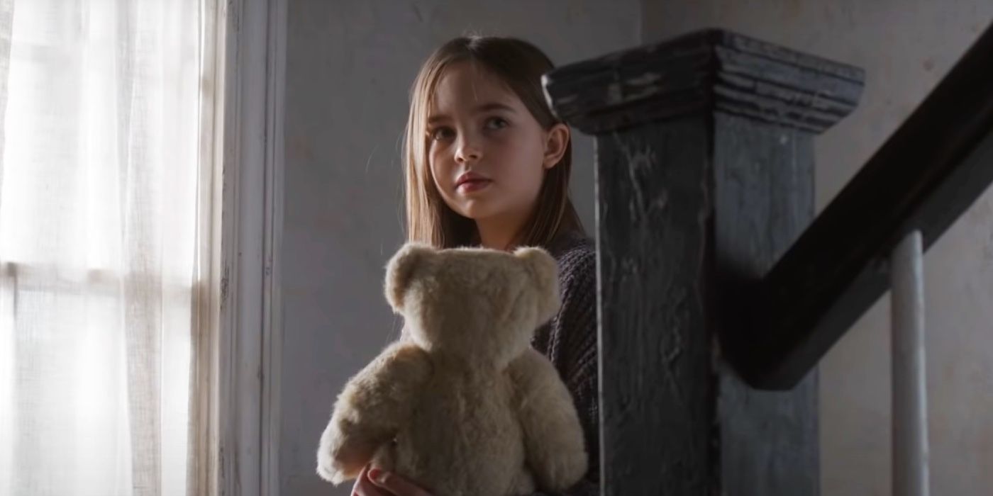 Alma holding a teddy bear and climbing down the stairs in American Horror Story Double Feature