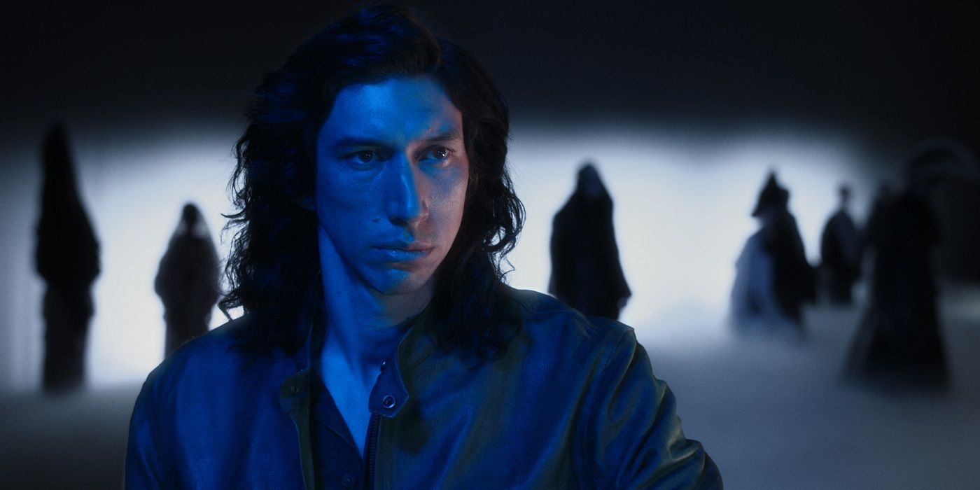 Adam Driver with hooded figures behind him in a scene from Annette