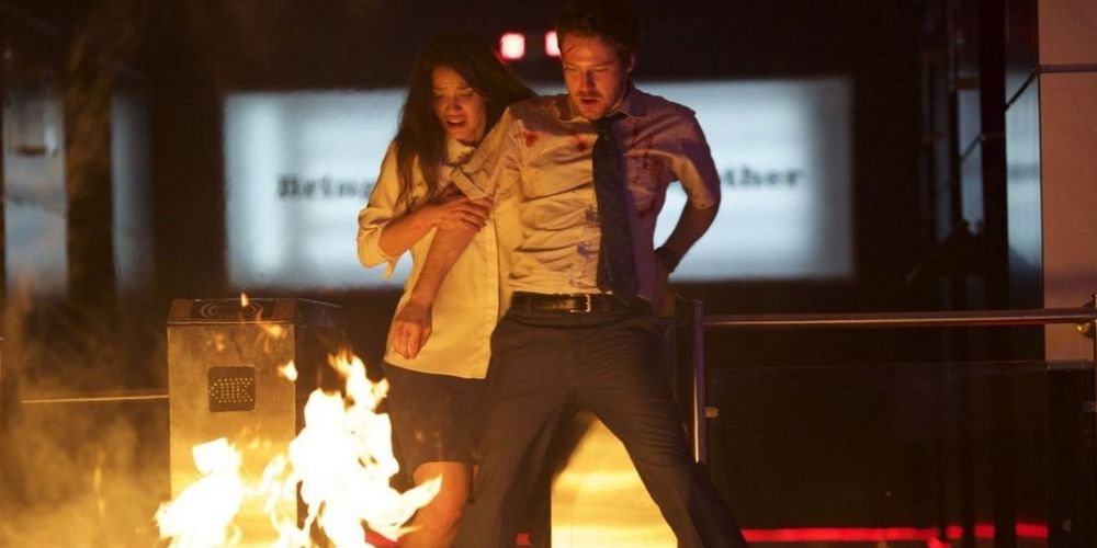 Mike and Leandra stand on a desk to avoid fire in The Belko Experiment