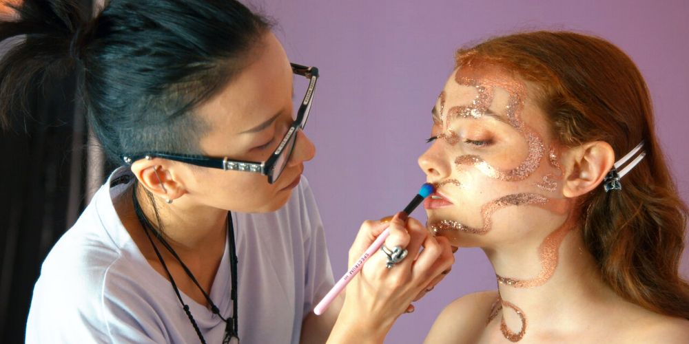 Makeup artists applies makeup on a female client in Glow Up: 
