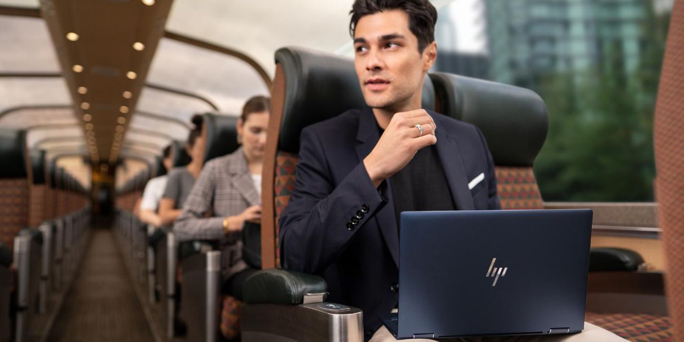 A man sitting on a plane with the HP DragonFly Elite laptop in his laptop.
