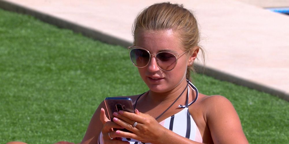 Amy reads text message outside of the the villa on Love Island