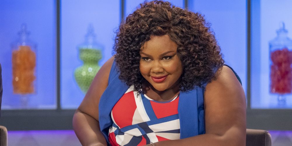 Nicole leans over the table to give her judgment on Nailed It!