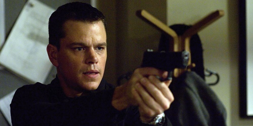 Jason Bourne holds two hands on a pistol in The Bourne Identity