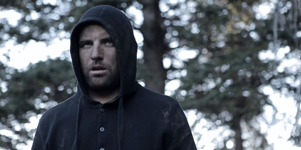 Ely wears a hood in the woods in A Monster Among Men
