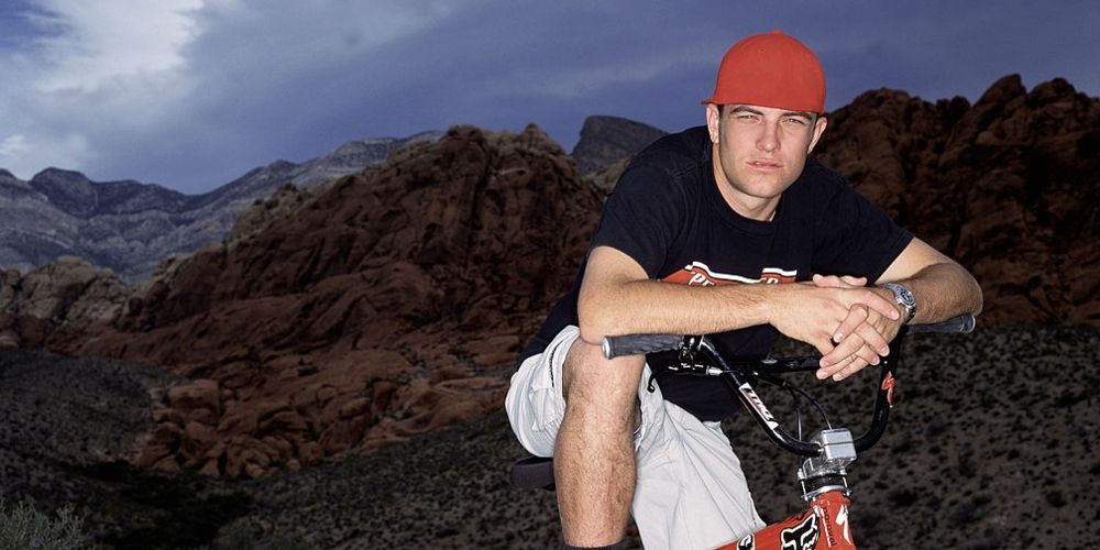 TJ lavin poses on his BMX bike at dusk by a mountainside