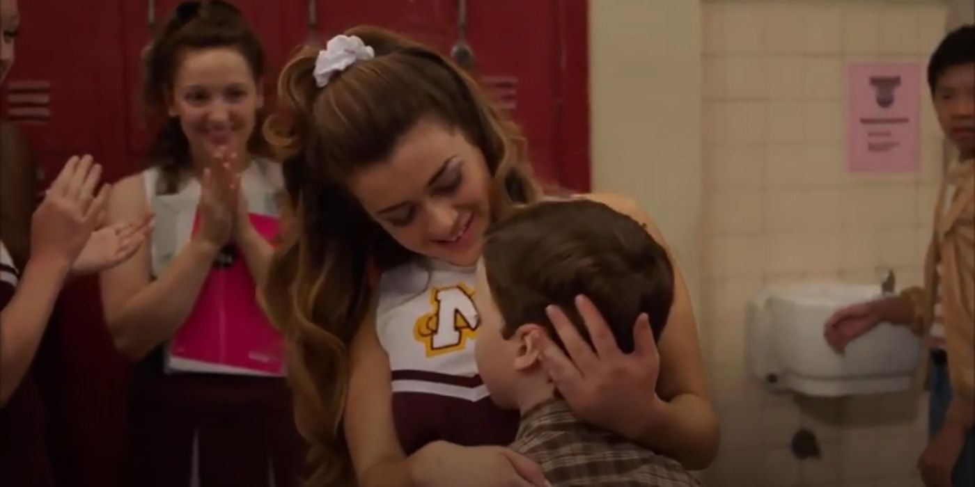 A cheerleader at school holding Sheldon's head to her chest on Young Sheldon.