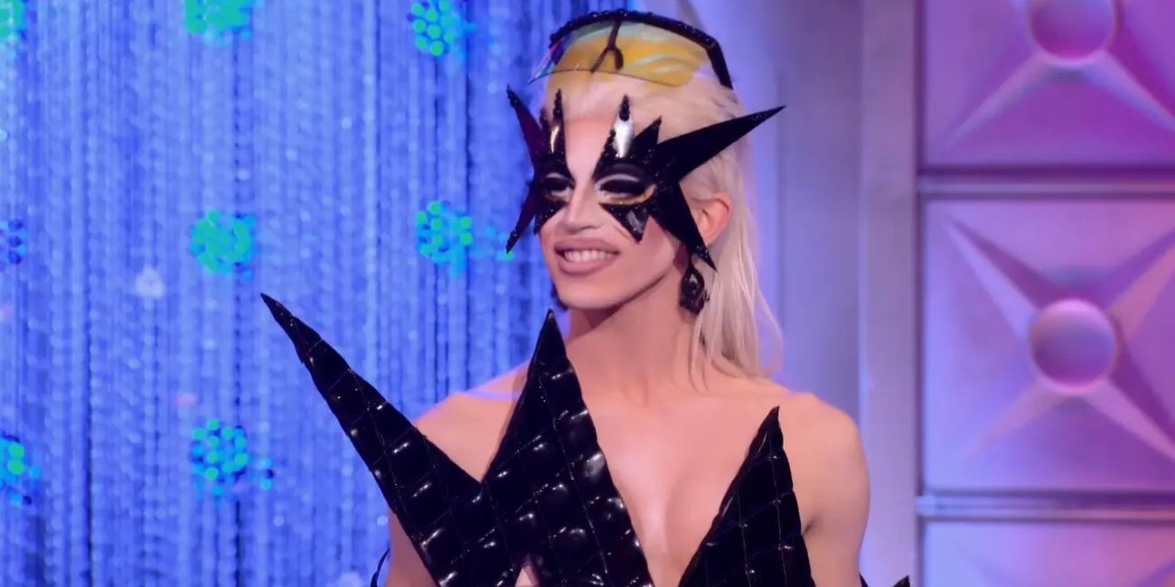 Aquaria sorri enquanto usa uma máscara preta em RuPaul's Drag Race.