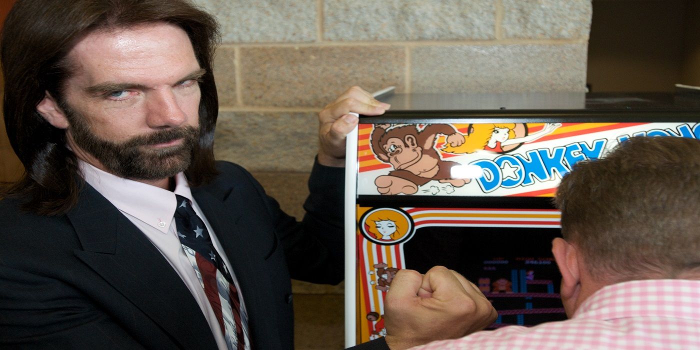 Billy Mitchell stands next to a Donkey Kong machine in King of Kong