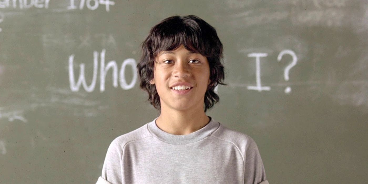 The titular character in Taika Waititi's Boy, standing in front of a blackboard and smiling