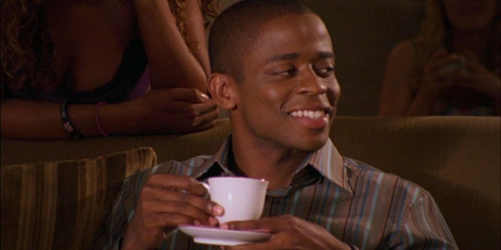 Burton Guster smiles nervously while holding a cup of tea in Psych