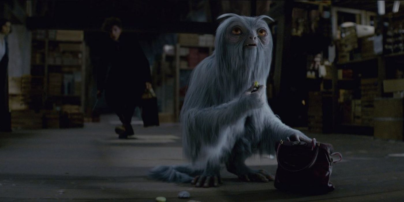 Dougal the Demiguise looking through a purse while Newt approaches in Fantastic Beasts