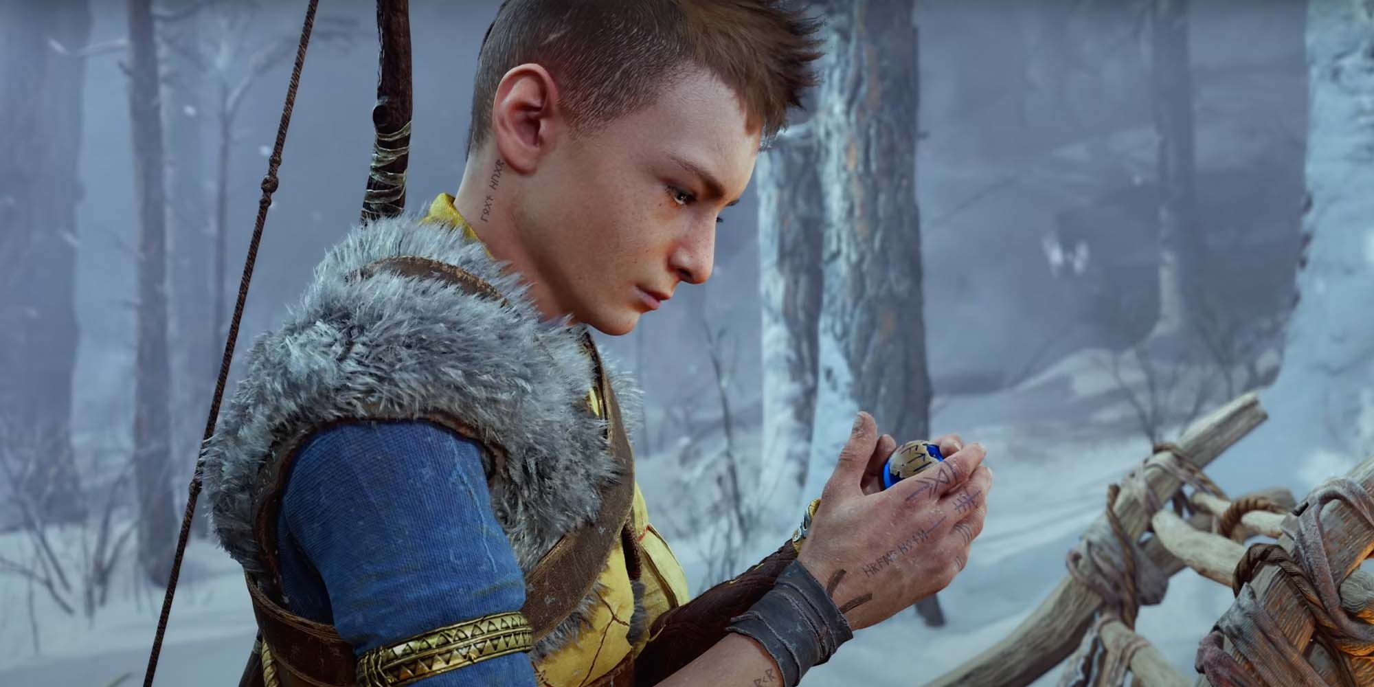 Atreus holding the blue orb in a snow covered forest in God of War Ragnarok.