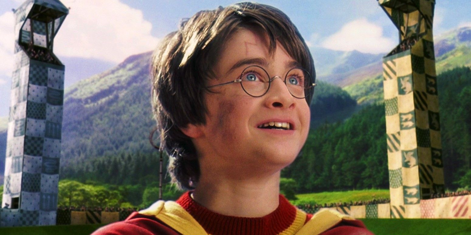 Harry Potter looks up and smiles on a Quidditch field in Harry Potter &amp; the Sorcerer's Stone.