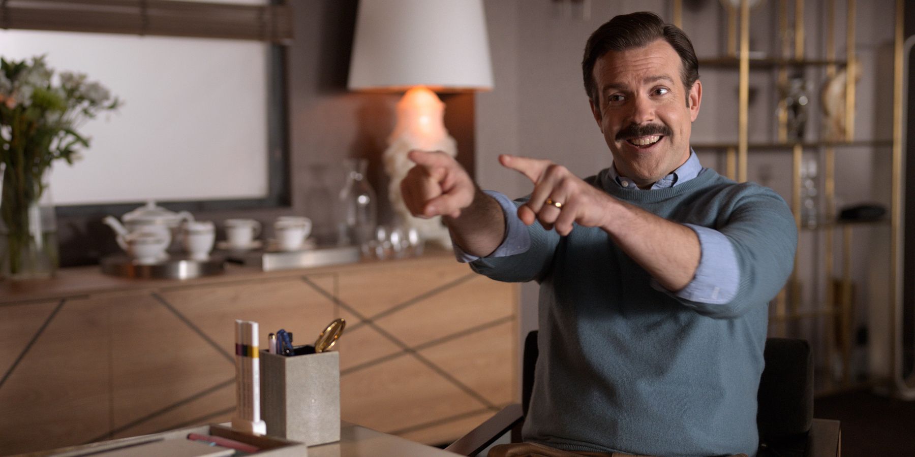 Ted Lasso smiling and pointing at someone with both hands