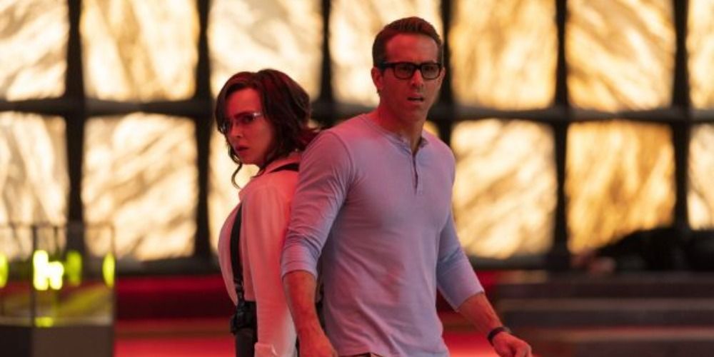 Jodie Comer and Ryan Reynolds in Free Guy stand back to back looking scared.