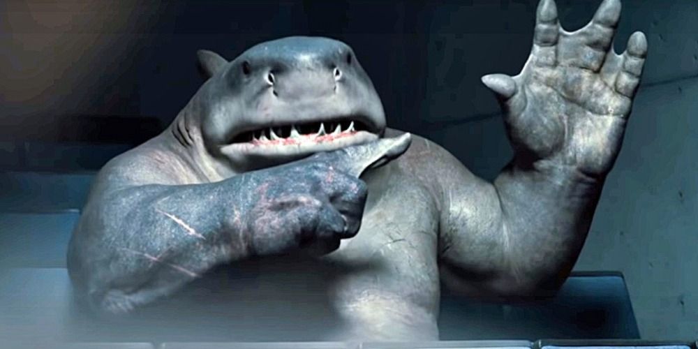 King Shark from The Suicide Squad holding up a hand and pointing at it