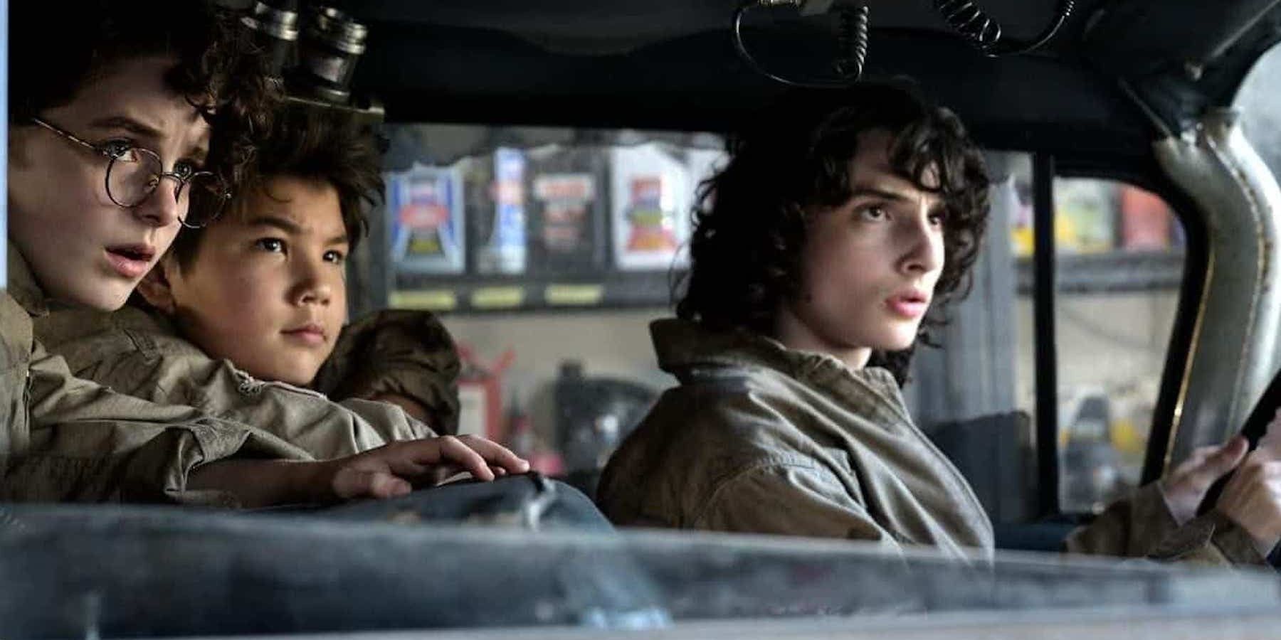 McKenna Grace, Logan Kim and Finn Wolfhard sit in Ecto 1 in Ghostbusters Afterlife