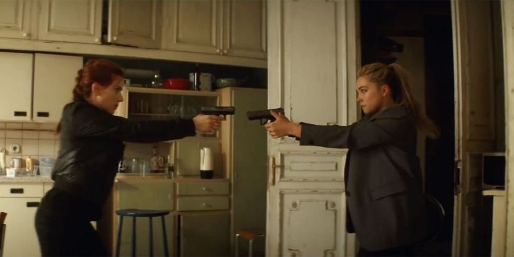 Natasha Romanoff and Yelena Bolova pointing guns at each other in a kitchen in Black Widow