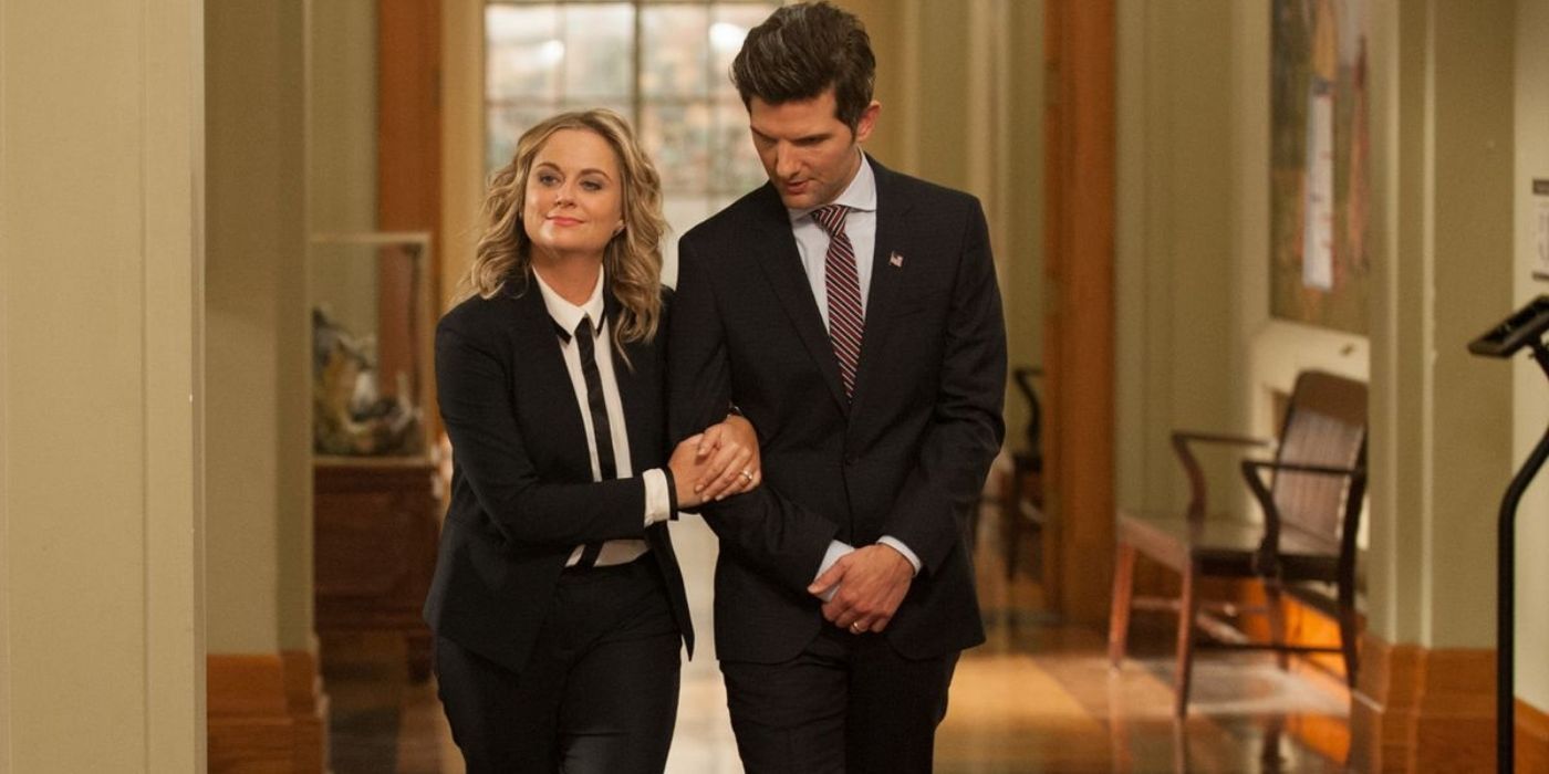 Leslie and Ben walking hand in hand down a hallway in Parks and Recreation.