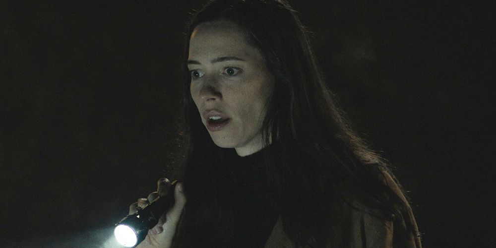 Beth shines a flashlight on the ground in The Night House
