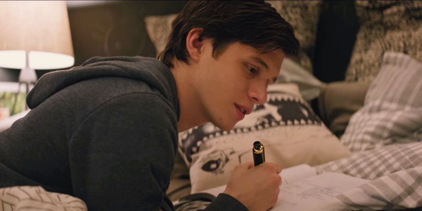 Simon sits on his bed and writes in his journal in Love, Simon.