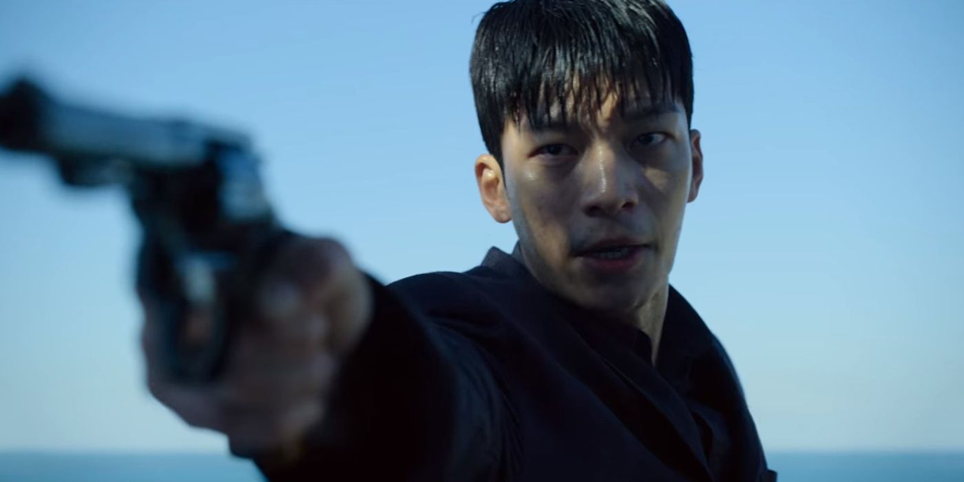 Jun-ho aims his gun against a blue sky and ocean in the distance in the Netflix show Squid Game.