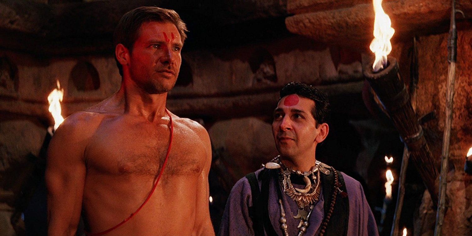 A shirtless Indy is possessed with a man standing beside him in Indiana Jones & the Temple of Doom.