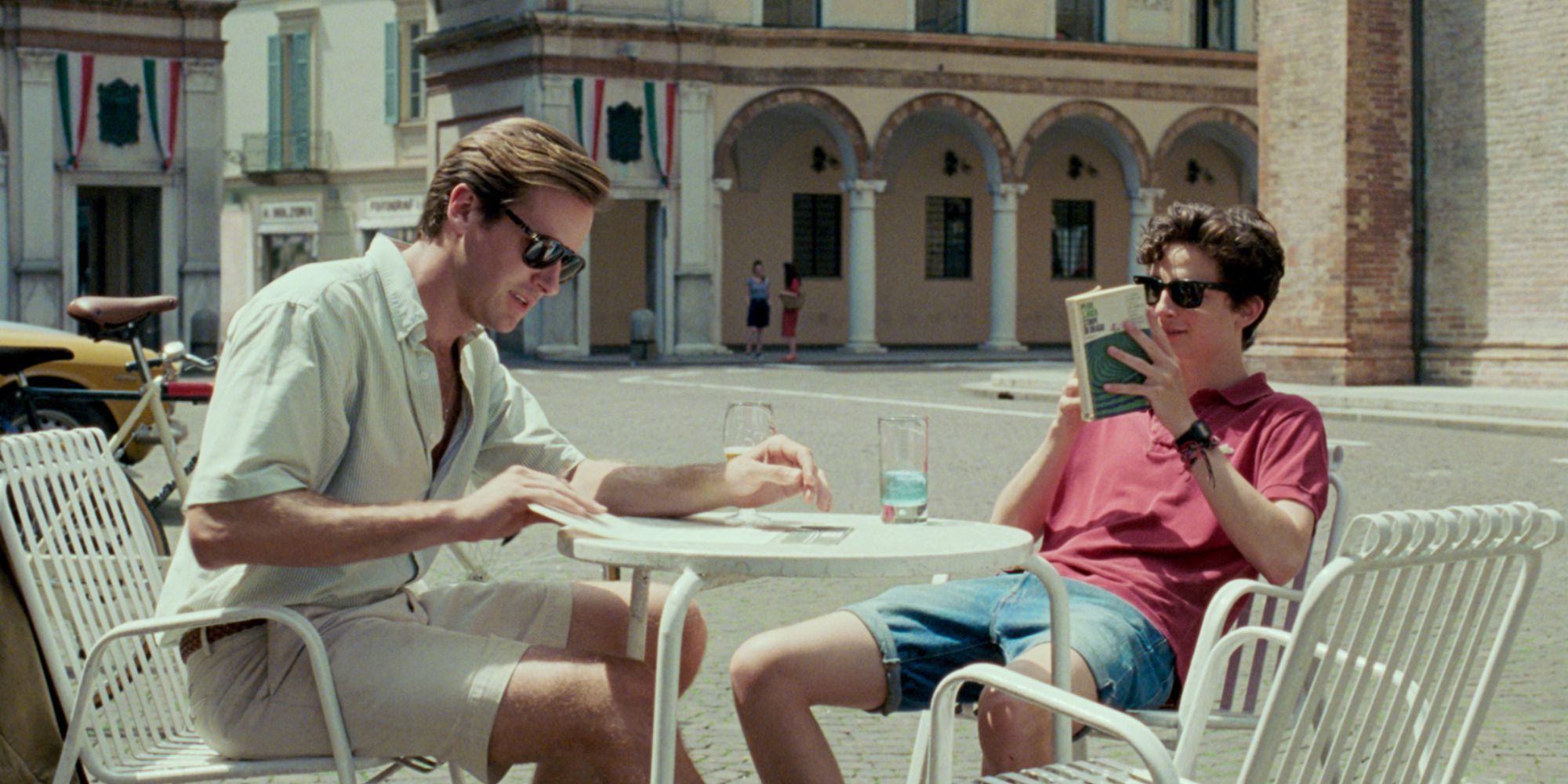 Timothée Chalamet and Armie Hammer in Call Me by Your Name sitting on a table together with drinks