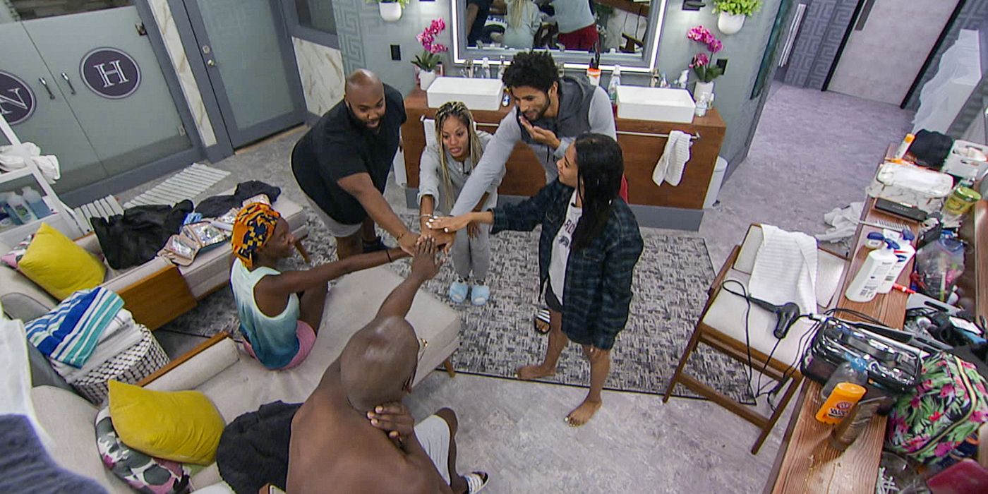 An overhead view of The Cookout alliance from Big Brother with their hands together.